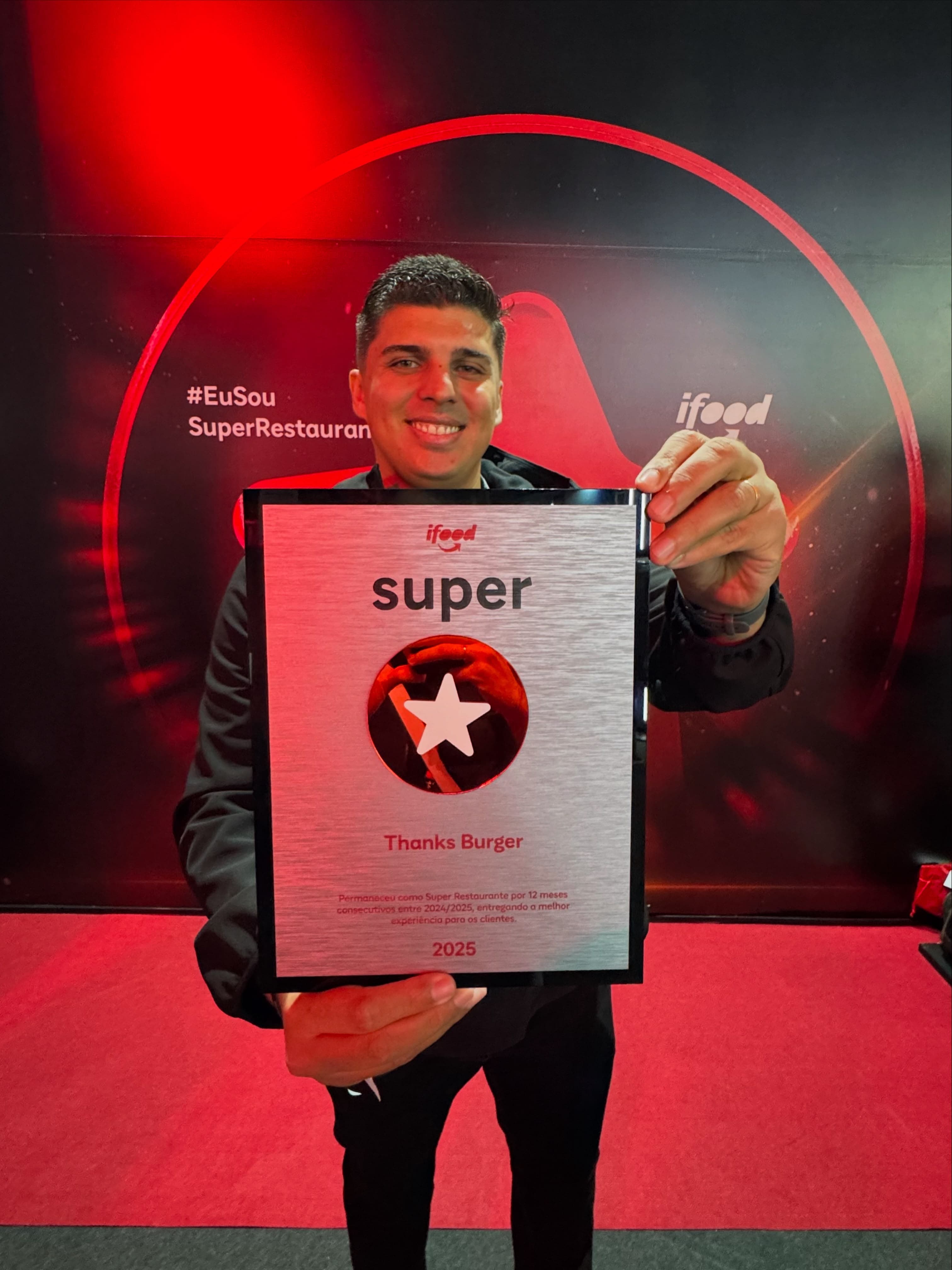 Lucas com a placa Super Restaurante do iFood